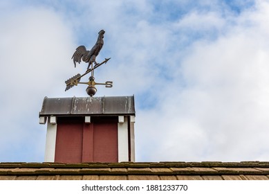 Copper rooster weathervane on top of red rooftop cupola with a blue sky and white clouds in the background
 - Powered by Shutterstock