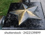 Copper star on a marble base in the park. five-pointed star - a symbol of the bygone Soviet era