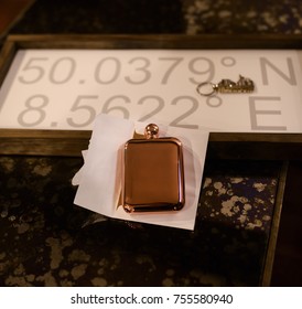 A Copper Whiskey Flask Given As A Gift To A Groom Sits On A Table.