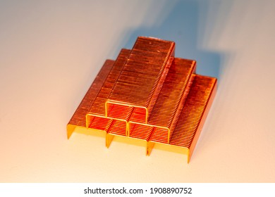 Coppered staples photographed close-up in white tones. Six groups of copper staples placed diagonally and forming a pyramid.