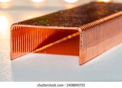 Coppered staples photographed close-up in white tones. Group of copper staples placed diagonally as if it were a tunnel with the light coming from behind.