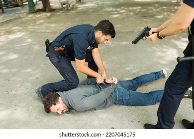 Cops Putting Handcuffs On A Violent Young Man Criminal And Making An Arrest Outdoors