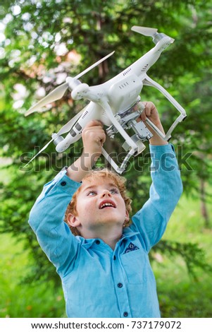 copter and boy,  boy playing with flying drone in sunny autumn garden, happy young boy  playing with unmanned aerial vehicle (quadrocopter) drone.