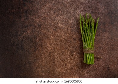 Copy Space With Asparagus At Rust Background. Bunch Of Asparagus In Right Corner Of Picture. Top View, Flat Lay, Lay Out, Free Space For Text