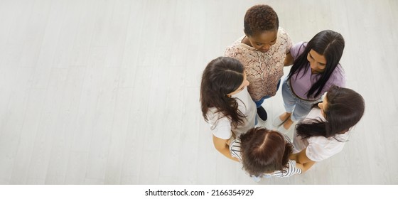 Copy Space Banner Background With Overhead View Of Team Of Five Happy Beautiful Modern Young Women Standing In Circle And Hugging Each Other. Unity, Aiming For One Goal, Female Support Group Concept