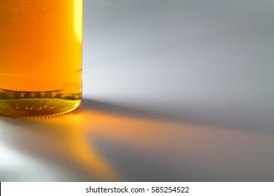 A copy space concept an apple juice  honey  yellow liquid in glass bottle illuminated by light and gradient yellow orange color shadow reflection  Isolated white background
