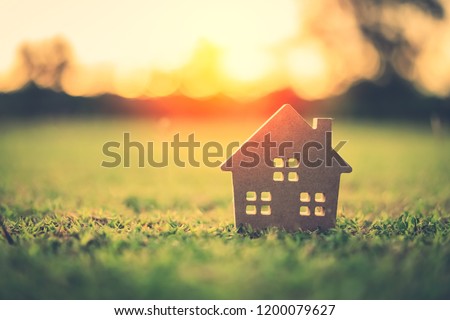 Copy space of home and life concept. Small model home on green grass with sunlight abstract background. Vintage tone filter effect color style.