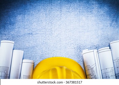 Copy space image of blueprints with protective hard hat on silver-metal vintage scratched surface construction concept.