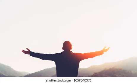 Copy Space Of Man Rise Hand Up On Top Of Mountain And Sunset Sky Abstract Background. Freedom And Travel Adventure Concept. Vintage Tone Filter Effect Color Style.