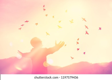 Copy space man rise hand up on top of mountain and sunset sky with birds fly abstract background. Freedom travel adventure and business victory concept. Vintage tone filter effect color style. - Shutterstock ID 1197579436