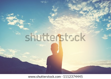 Copy space of man rise hand up on top of mountain and sunset sky abstract background. Freedom travel adventure and business victory concept. Vintage tone filter effect color style.