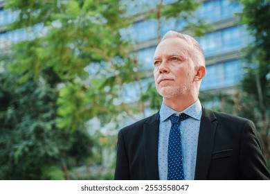 Copy Space. A Mature, Experienced Businessman Thoughtfully Gazes Out at the Lush, Verdant Surroundings Visible through the Office Windows. Mid Adult Male Appearing Contemplative and Introspective - Powered by Shutterstock