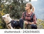 copy space mountain travel woman with her dog in her arms, woman and dog communicate while sitting in the mountains, hiking on a sunny day. In the woods. with a backpack. Travel companion.