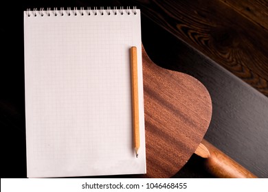 copy space on a dark background of chestnut color. ukulele guitar with nylon strings