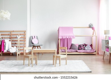 Copy Space On Empty White Wall In Trendy Pink And Bright Girly Bedroom With Wooden Furniture And Toys