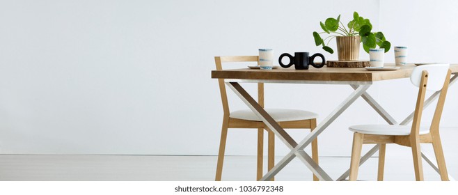 Copy space on white wall in empty dining room interior with chairs at wooden table