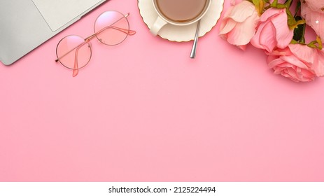 Copy space for product display or presentation background with laptop, eyeglasses, teacup and roses on pink background. top view