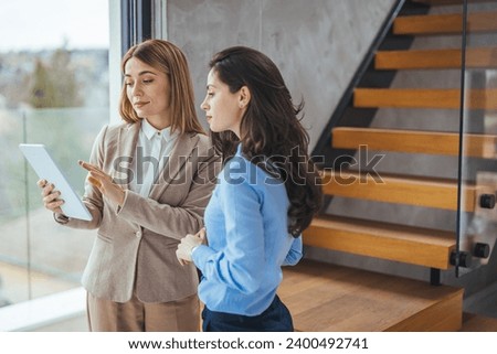 Copy space shot of two young businesswomen walking to a meeting together and looking at data on a digital tablet one of them is holding. They've just discovered something amazing online