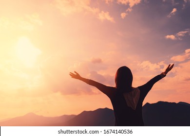 Copy space of silhouette woman raise hand up on top of mountain and sunset sky cloud abstract background. Freedom feel good and travel adventure holiday concept. Vintage tone filter effect color style