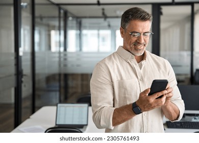 Copy space are with smiling mature Latin or Indian businessman holding smartphone in office. Middle aged manager using cell phone mobile app. Digital technology application and solutions for business. - Powered by Shutterstock