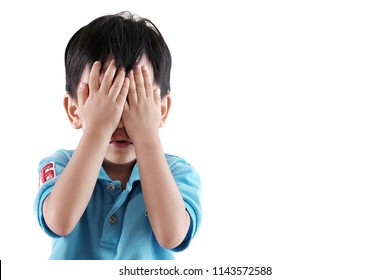 Copy space and Soft focus at little Asian boy covering his face with hands and playing hide and seek. Background with white color. Concept of kid activity, 