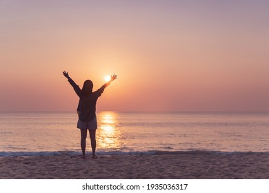 Copy space of woman rise hand up on sunset sky at beach and island background. Freedom and travel adventure concept. Vintage tone filter effect color style.