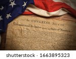 A copy of the United States Declaration of Independence with a vintage American flag on a wood background