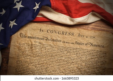 A copy of the United States Declaration of Independence with a vintage American flag on a wood background - Shutterstock ID 1663895323