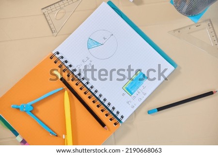 Copybook with geometry examples for solving in primary school. Drawing compass and school supplies on the table. Leaning new subject on new semester of academic year. Education background concept.