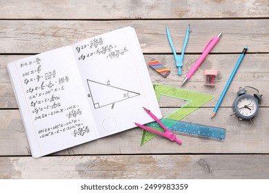 Copybook with maths formulas and stationery on grey wooden background