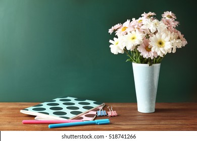 Copybooks And Flowers On Teacher's Desk