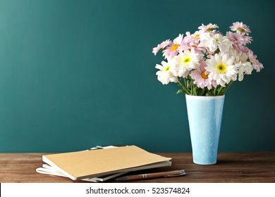 Copybooks And Flowers On Teacher's Desk