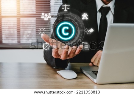 Copyright or patent concept, Business person hand holding VR screen copyright icon with blue bokeh background, Copyleft trademark license, Creation ownership against piracy crime. 