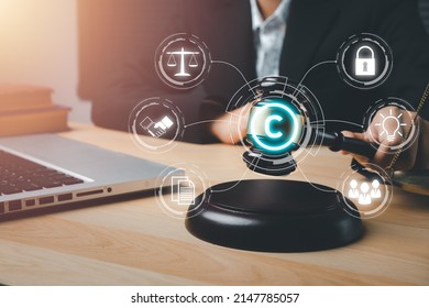 Copyright or patent concept, Woman hand holding judge gavel on desk with VR screen copyright icon background, Copyleft trademark license, Creation ownership against piracy crime.	