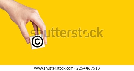 Copyright sign, symbol in hand, banner. Intellectual property protection, patent law on yellow background. High quality photo