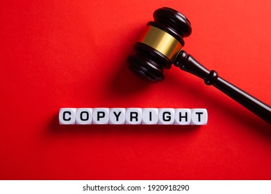 Copyright word and a judge gavel on red background. Concept of legal education.
