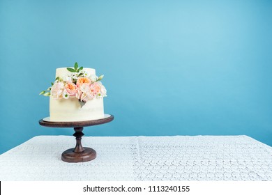 Copyspace Mockup Working Space Baker Confectioner Pastry Chef Appetizing Creamy White Two-tiered Wedding Cake Decorated With Fresh Flowers On A Table Studio On A Blue Background