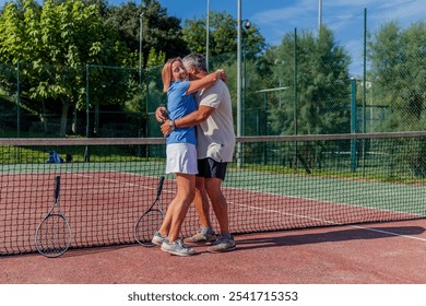 copyspace senior couple of tennis players shares triumphant hug after winning their match on the club court. Their joyful expressions and warm embrace highlight their love for each other and the sport - Powered by Shutterstock