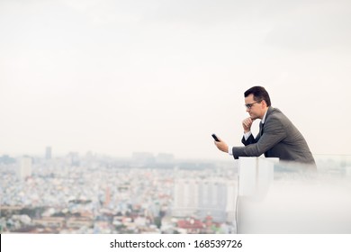 Copy-spaced image of a businessman making a telephone call while standing on the roof  - Powered by Shutterstock