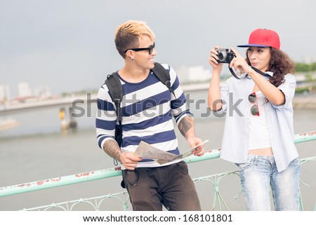 Copy-spaced image of a couple where a woman making a photo of a young man on the foreground 