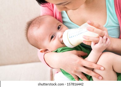 Copy-spaced image of a mother feeding her little baby boy from the milkbottle on the foreground