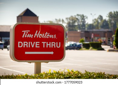 Coquitlam, BC / Canada - July 15th 2020: A Shot Of A Tim Hortons Drive Thru Sign Pointing At A Busy Franchise Location In Coquitlam British Columbia