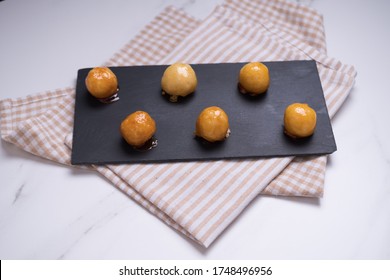 Coquitos Coconut Balls With Caramel On Black Slate On Squared Rag On White Marble