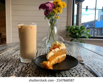 Corbin, Kentucky - April 16, 2022: Carrot cake and iced latte with a flower center piece at folktale coffee and bake house