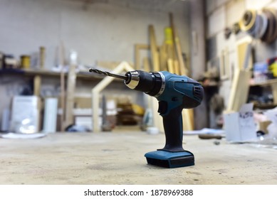 Cordless combi drill for used as impact drill and screw driver. Cordless impact screwdriver for work with self-tapping screws. Brushless battery drill on a wooden workbench in furniture workshop
