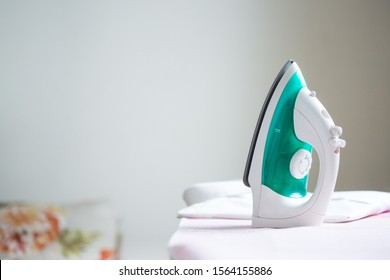 cordless iron on a pink ironing board next to a folded shirt 