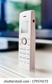 Cordless Phone On Office Table - White Color And Large Display. Tilt-shift Lens Used To Accent The Center Of The Phone And To Emphasize The Attention Its Central Buttons