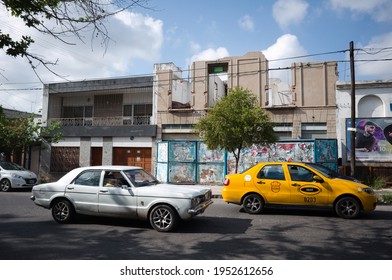 Cordoba, Argentina - January 2020: Old Vintage Car, Yellow Taxi And Destroyed Two-story Building On Background. Dilapidated, Derelict House On The City Street In Non-tourist Area  Of Buenos Aires