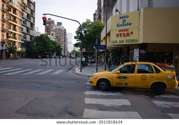 Cordoba, Argentina - January, 2020: Old\
restaurant with inscription Cafe, Bar and Pizzeria at corner of\
Avenida Maipu and 25 de Mayo streets. Yellow taxi at crossroads at\
pedestrian crossing.