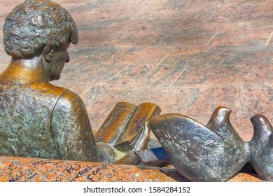 Cordoba,Spain 06/15/2918: Bronze Statue Woman Sitting Reading In A Park Bench